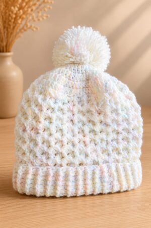 Handmade cream crochet hat with textured stitch detail, pastel flecks and faux fur pom-pom.