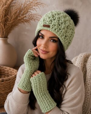 Handmade soft sage green crochet hat with pom-pom and matching fingerless gloves worn by a woman. Soft Sage Hat & Gloves Set by MTD Crochet.